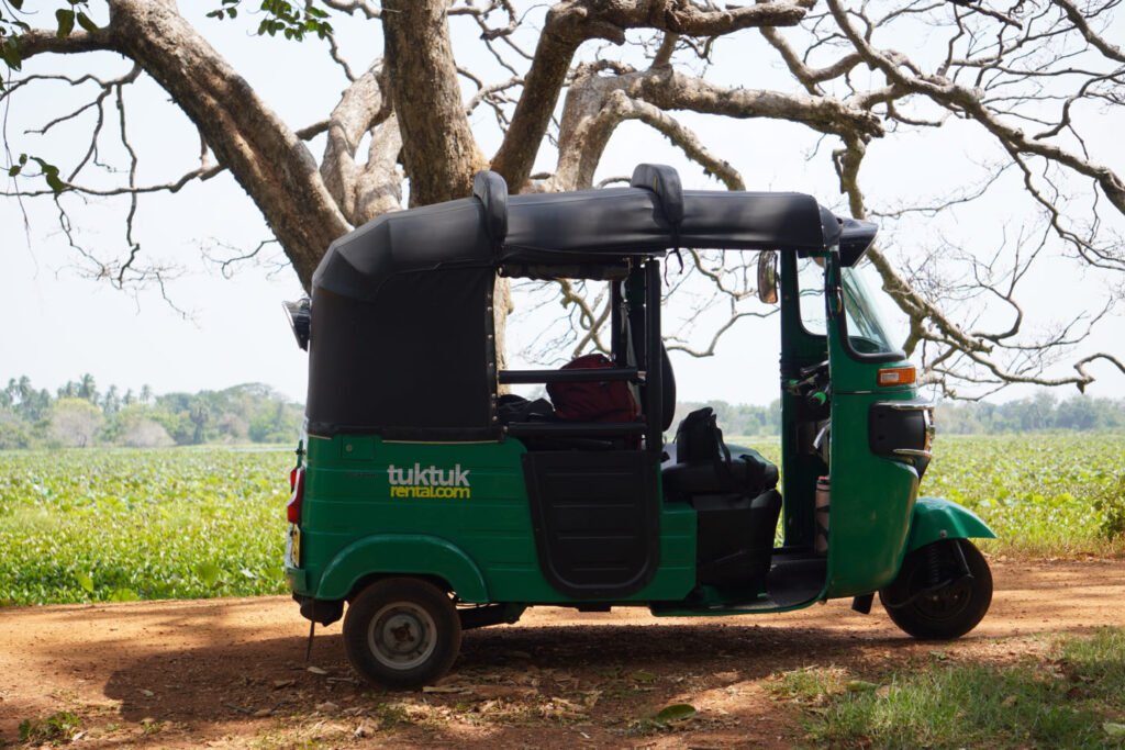 Groene huurtuktuk geparkeerd onder een grote boom in Sri Lanka