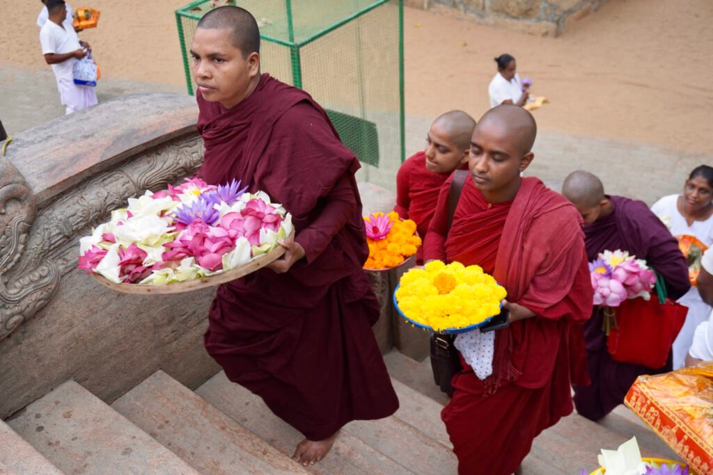 Monniken met bloemenoffers op de trap naar de heilige boom in Anuradhapura
