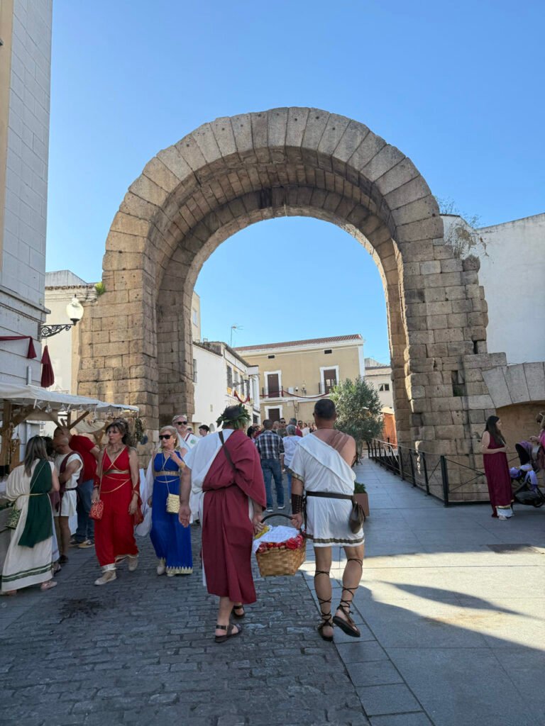Menschen in römischer Kleidung am Trajansbogen in Mérida