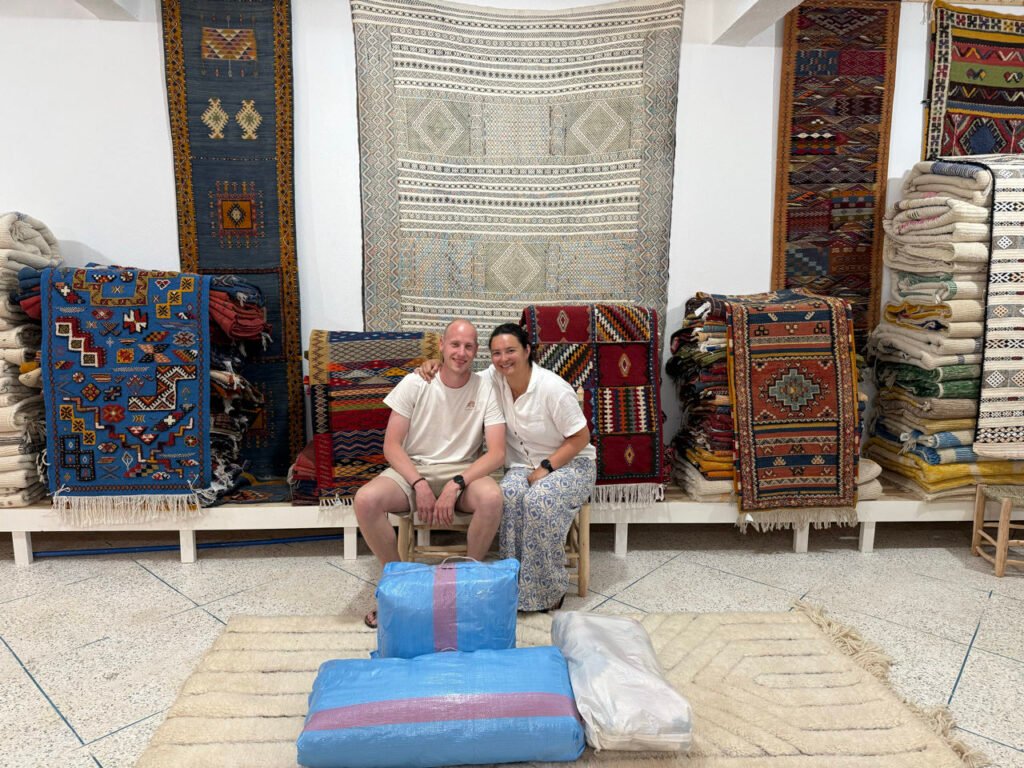 Julian und Florine mit ihrem eingepackten Teppich in einer Weberei bei Ouarzazate