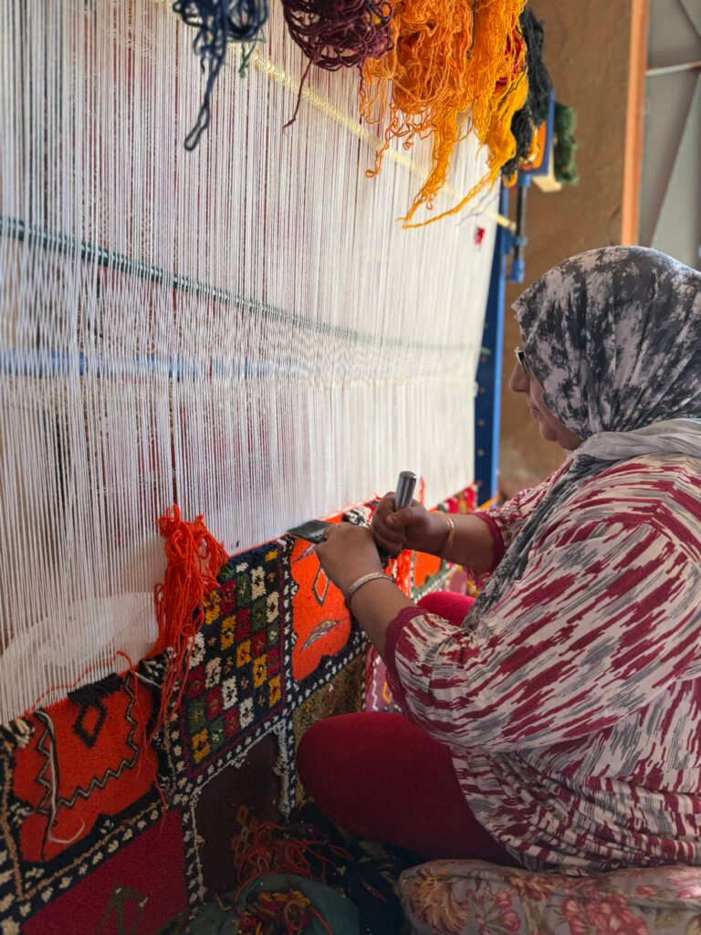 Frau knüpft einen Teppich an einem Webstuhl in einer Kooperative bei Ouarzazate